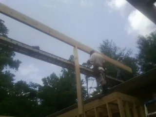 Carpenter setting a ridge beam over a new addition frame — Ice Dam Removal by Roofing Brothers in Remington