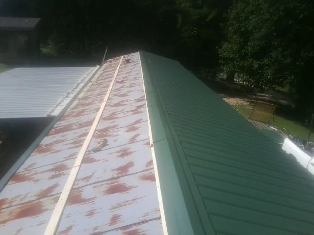 Old rusted panels beside newly installed green metal roofing — Wind Damage Roof Repair by Roofing Brothers in Remington