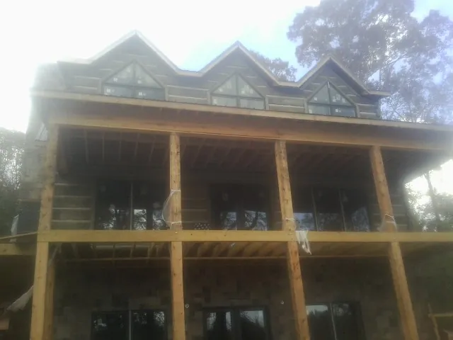 Dormers and porch framing on a large log home under construction — Roof Coating work by our crew in Remington