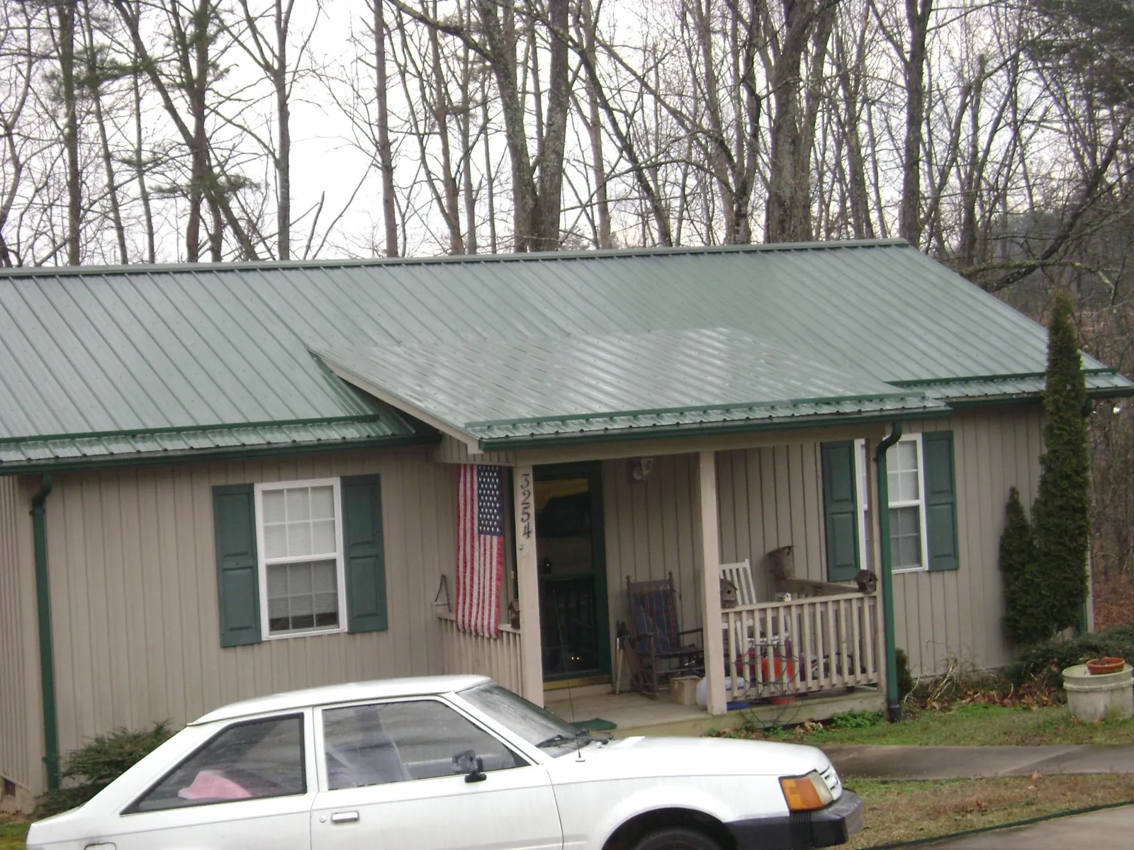 Green metal roof and front porch on a tan sided cottage in Remington
