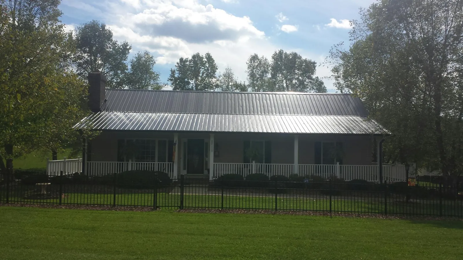 Gray metal roof on a brick ranch with a full width front porch — Gutter Guard Installation work by our crew in Remington