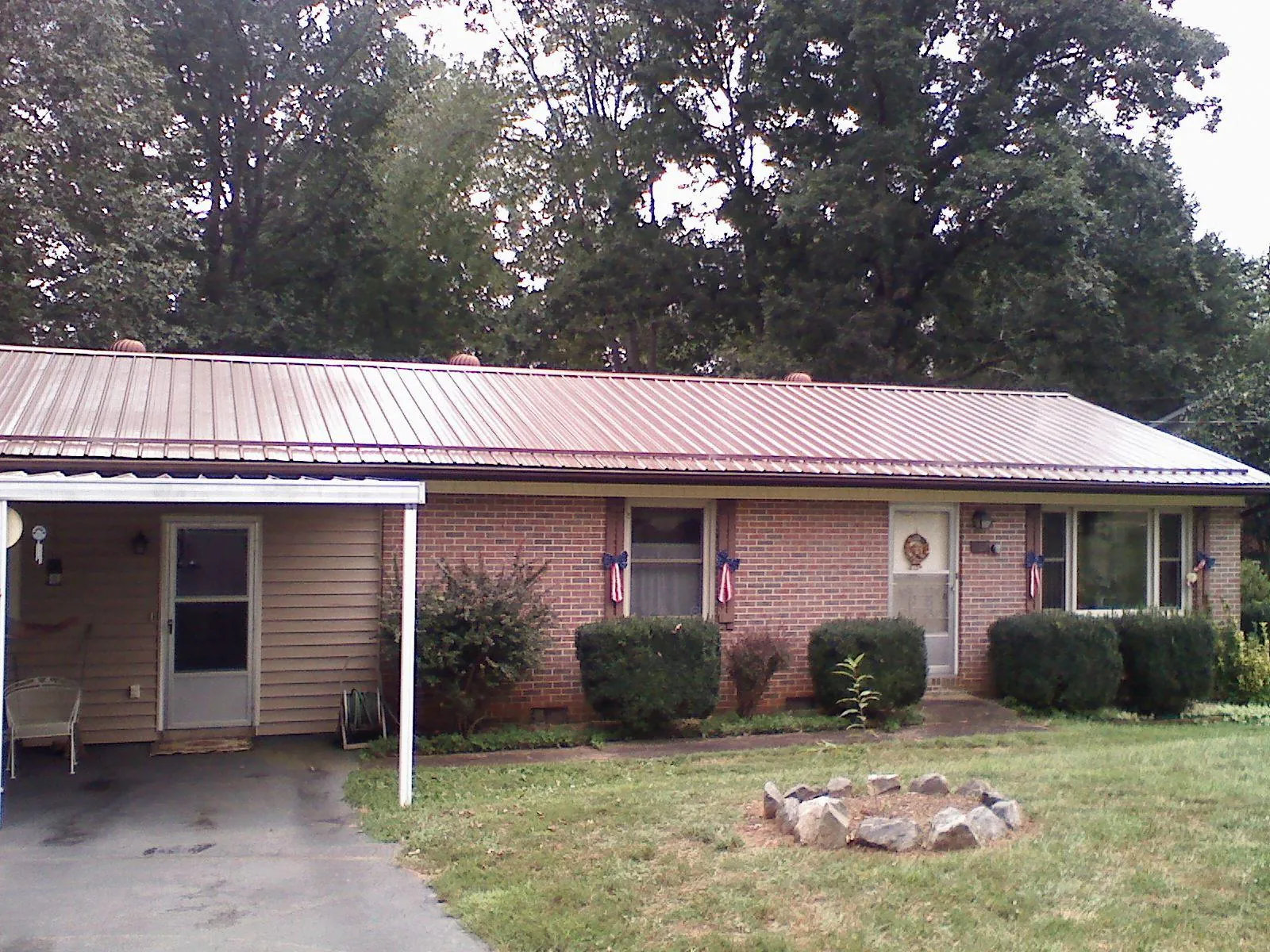 Bronze metal roof and carport on a brick ranch home — Roof Repair work by our crew in Remington