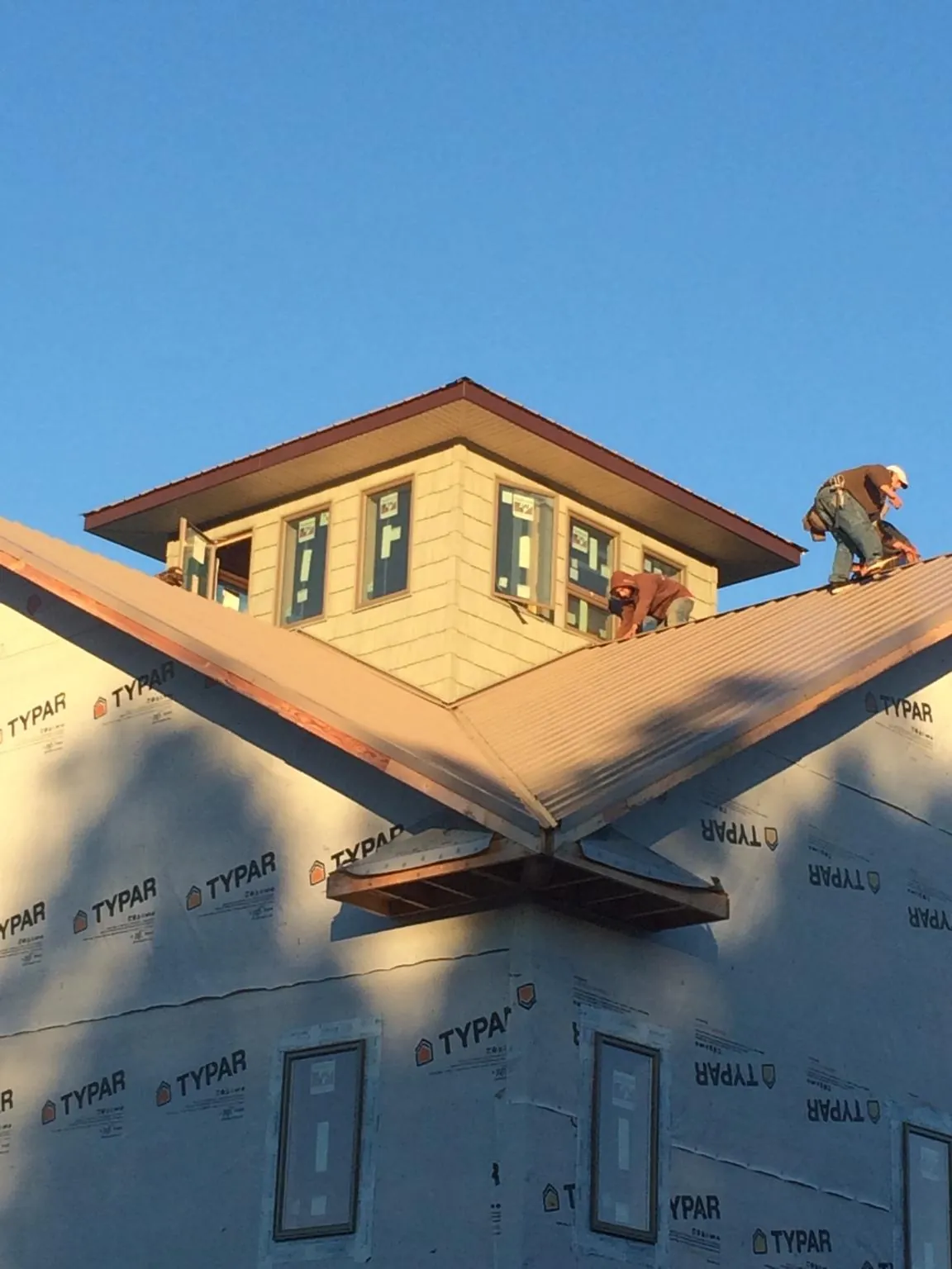 Roofers working around a rooftop cupola on a new metal roof at sunset — Roof Waterproofing in Remington by Roofing Brothers